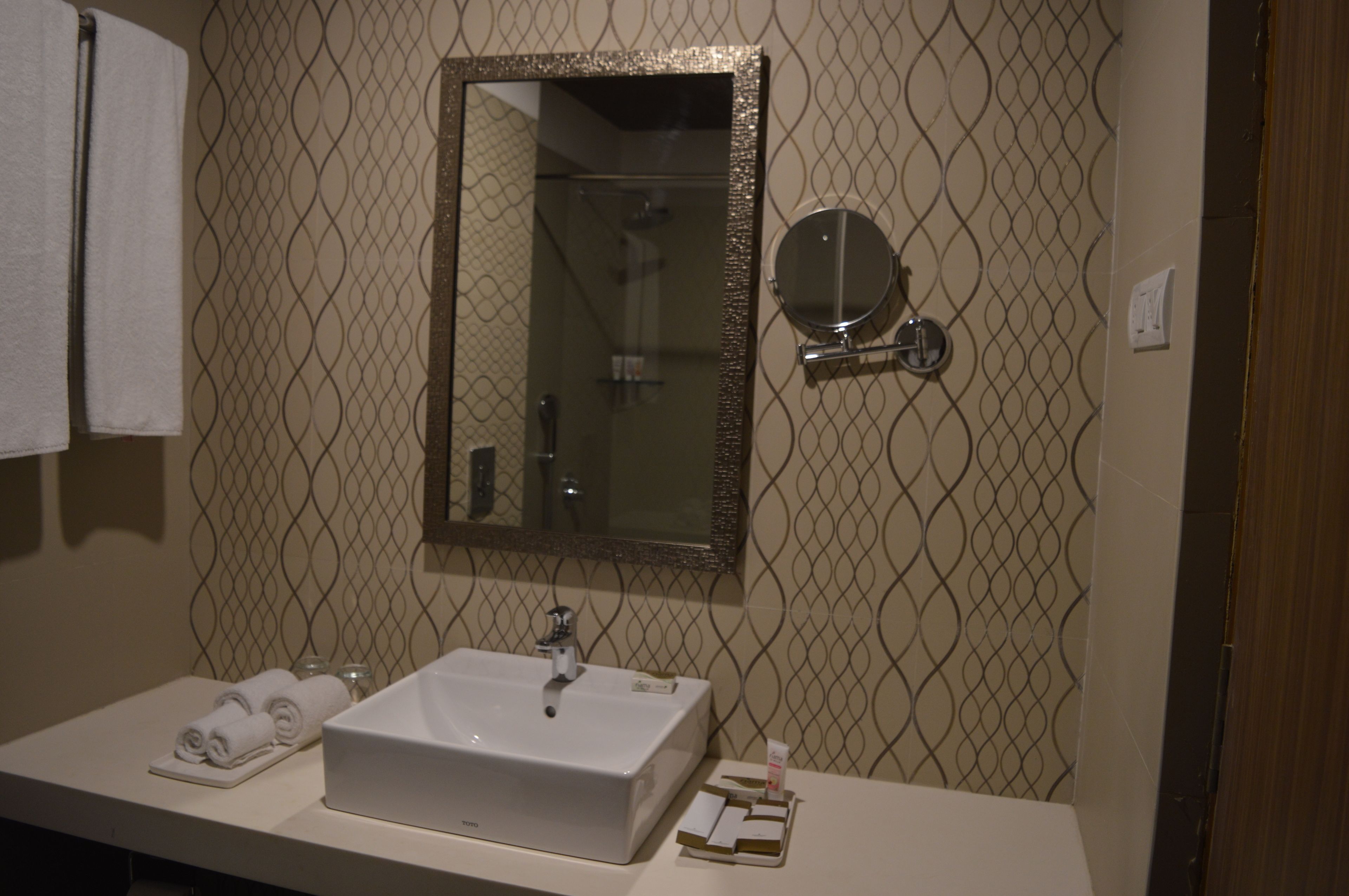 A bathroom with a white sink, a large mirror, and a towel rack.