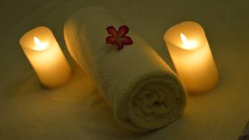 Tre candele accese e un asciugamano arrotolato con un fiore su un tavolo.