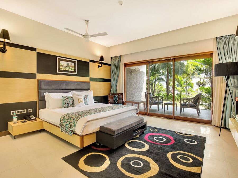 Habitación de hotel moderna con cama, mesita de noche, lámpara y vistas al exterior.