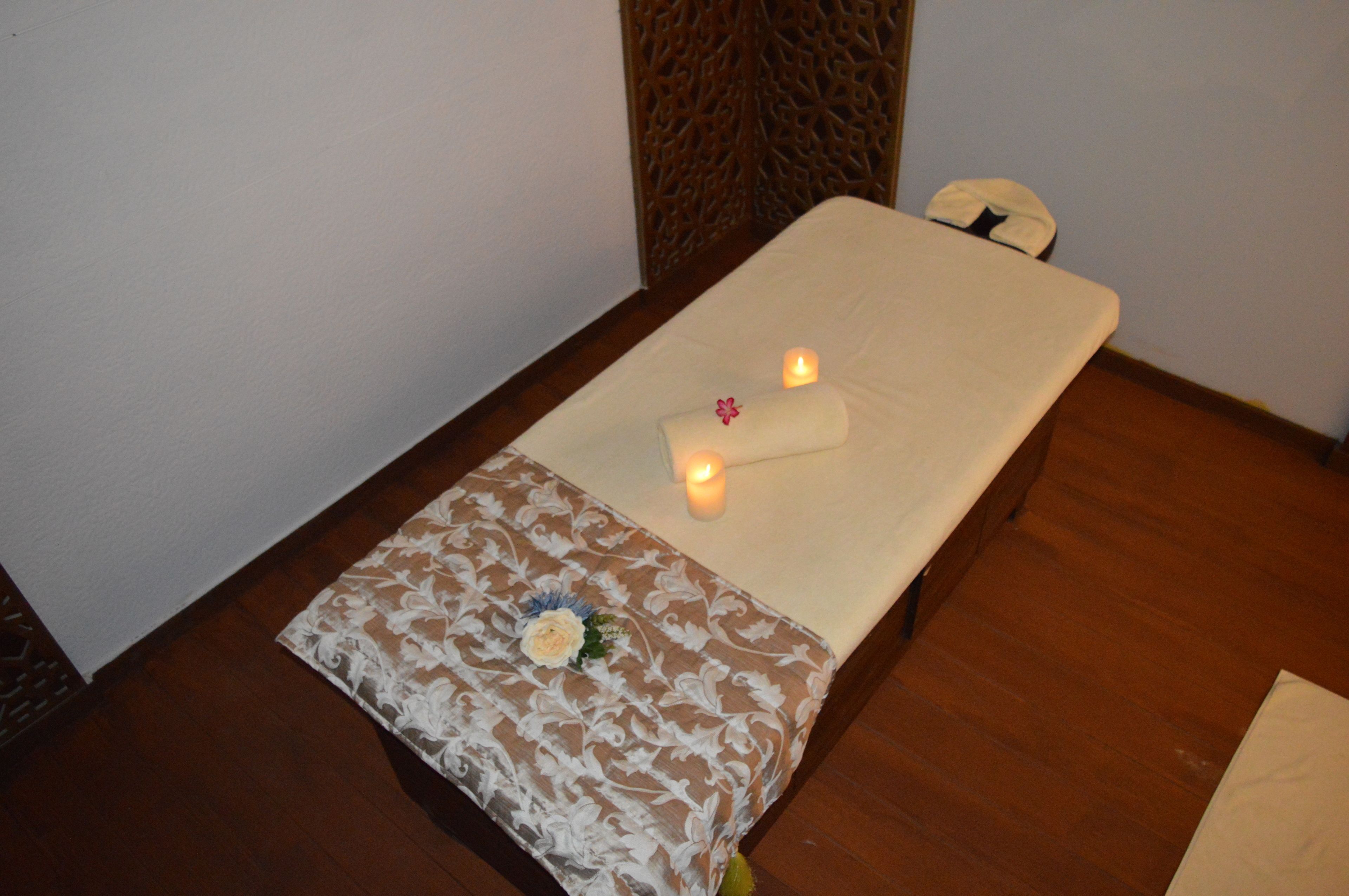 A small, neatly arranged room with a bed, two candles, and a decorative pillow.