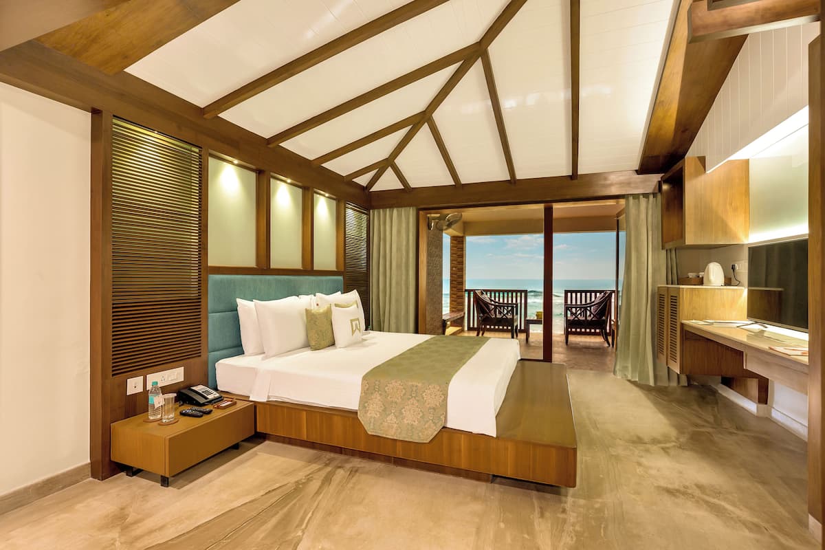 Habitación de hotel con cama, mesita de noche y vistas al mar.