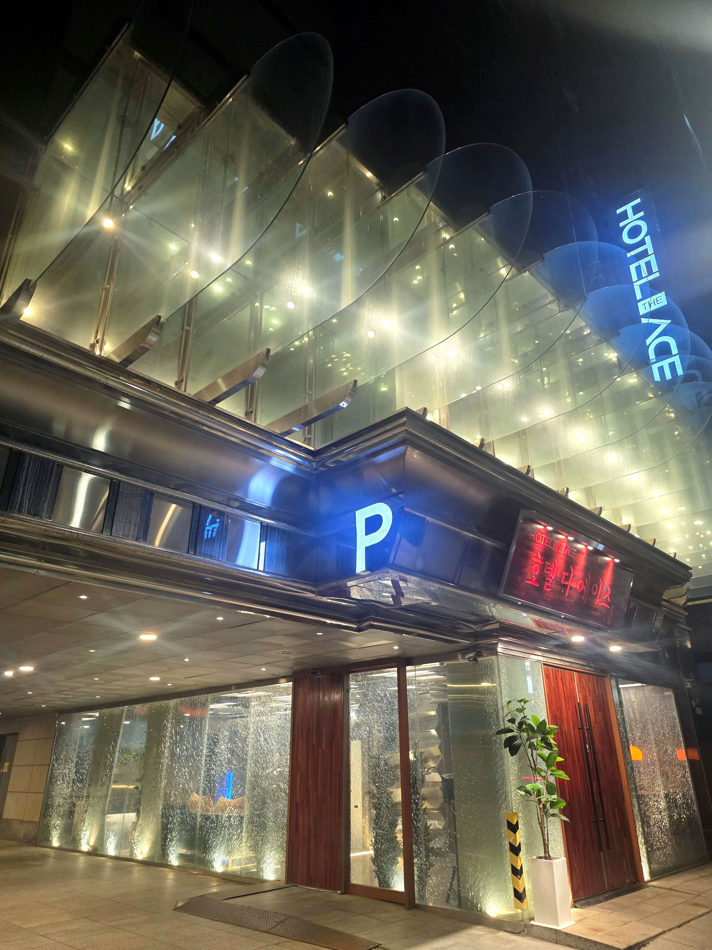 A hotel entrance with a prominent 'P' sign, glass facade, and a 'HOTEL LANCE' sign.