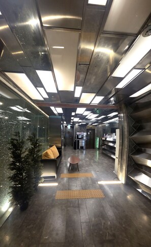 Un interior moderno con una zona de estar central, un mostrador de recepción y una escalera.
