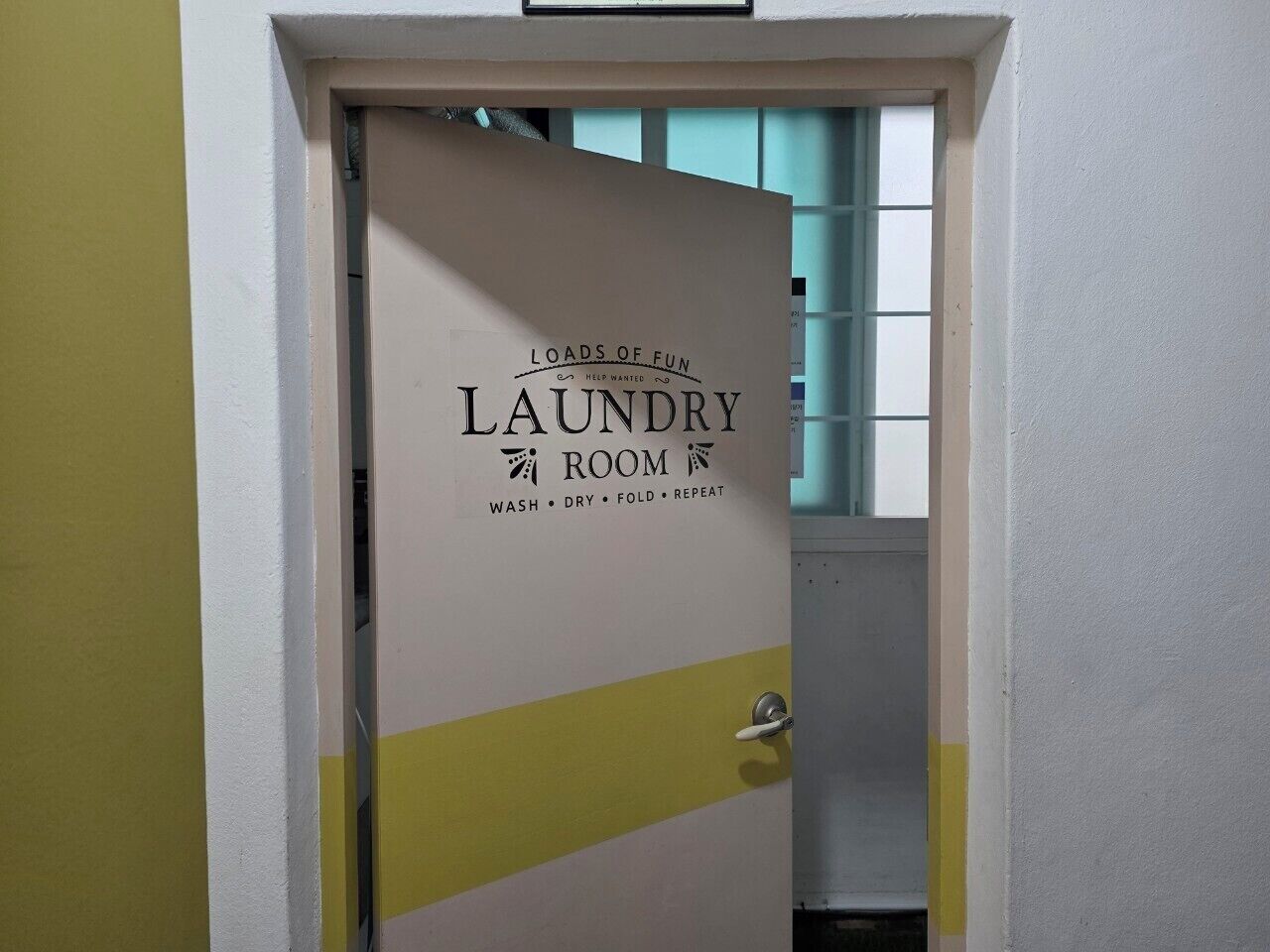 A door with a sign indicating a laundry room with steps leading to it.