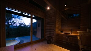 A cozy cabin interior with a wooden floor, a dining table, a sink, and a television mounted on the wall. - Shukubo Kawaseminoshou - The Kingfisher resort - (Taketa)