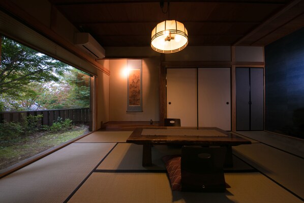 Um quarto japonês tradicional com tatames, uma mesa baixa e portas deslizantes.
