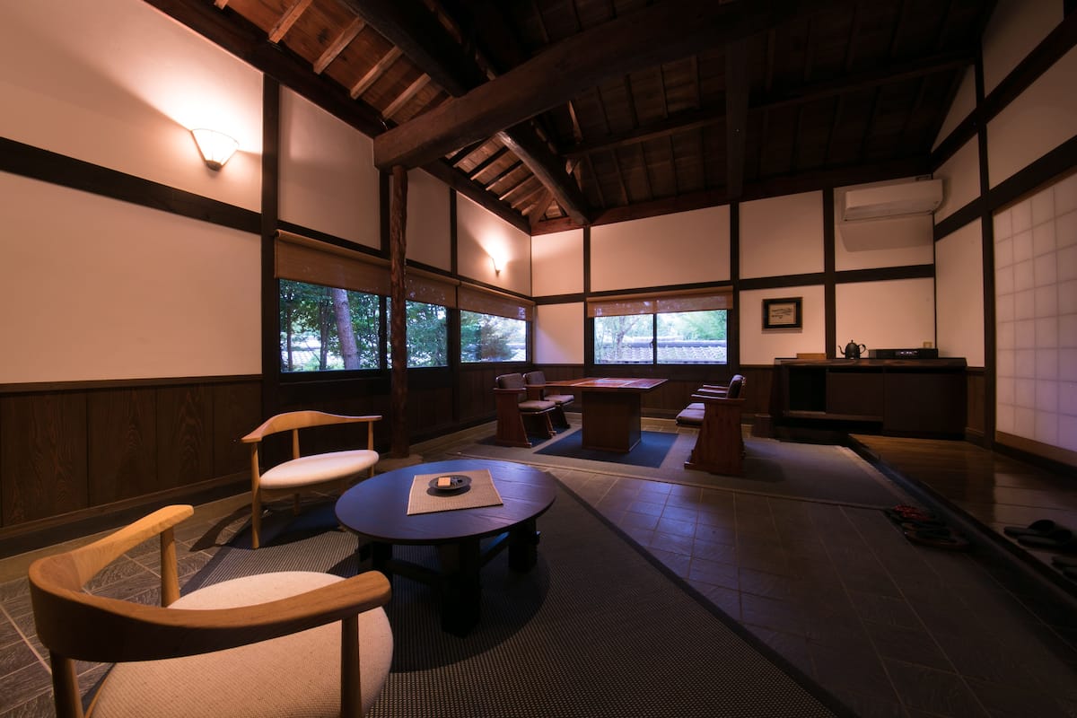 Ein traditioneller japanischer Raum mit Tatami-Böden, niedrigen Holztischen und Stühlen.