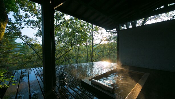 A wooden deck with a hot tub and a view of a forest. - Shukubo Kawaseminoshou - The Kingfisher resort - (Taketa)