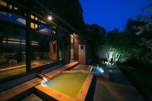 Un bâtiment moderne doté de grandes fenêtres en verre, d’une terrasse en bois et d’un petit espace piscine.