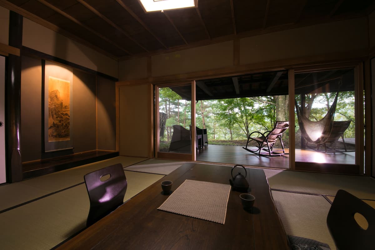Ein traditioneller japanischer Raum mit Tatami-Böden, einem niedrigen Tisch und Blick ins Freie.
