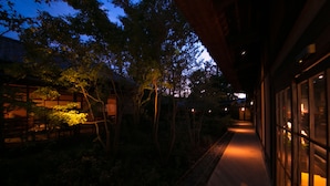 A pathway leading to a building with a traditional architectural style, surrounded by trees and a well-maintained garden. - Shukubo Kawaseminoshou - The Kingfisher resort - (Taketa)