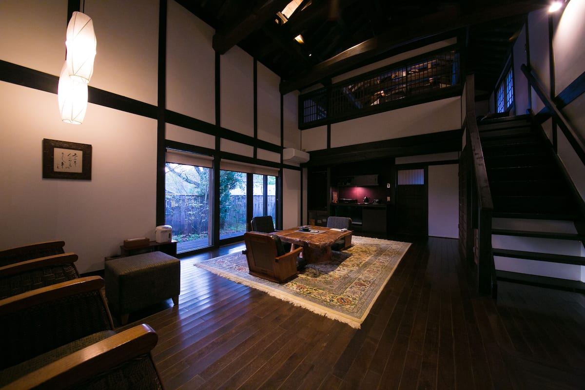 Ein traditioneller japanischer Raum mit Tatami-Bodenbelag, einem niedrigen Holztisch und einem großen Fenster.