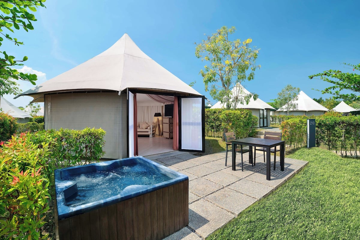 Un espace extérieur aménagé avec une tente, un jacuzzi, une table et des chaises.