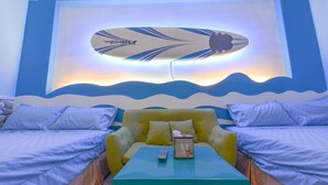 A room with a bed, two armchairs, a small table, and a wall-mounted surfboard decoration. - Minsuku (Taitung)