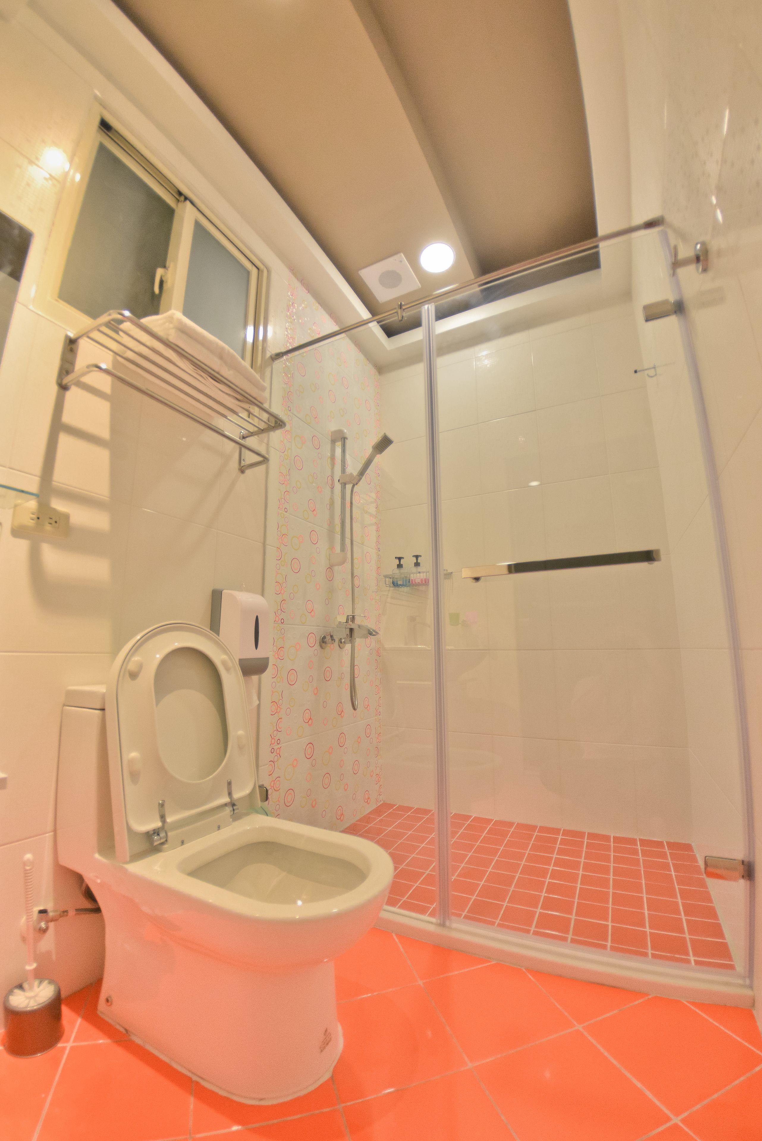 A bathroom with a toilet, a shower enclosure, and a window.