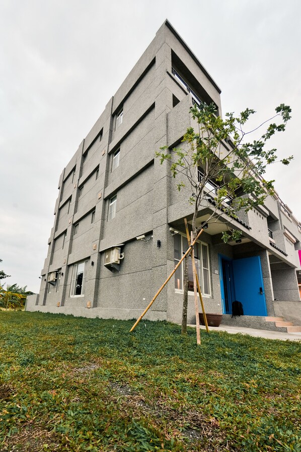 A modern building with a blue door and a small tree in front. - Minsuku (Taitung)