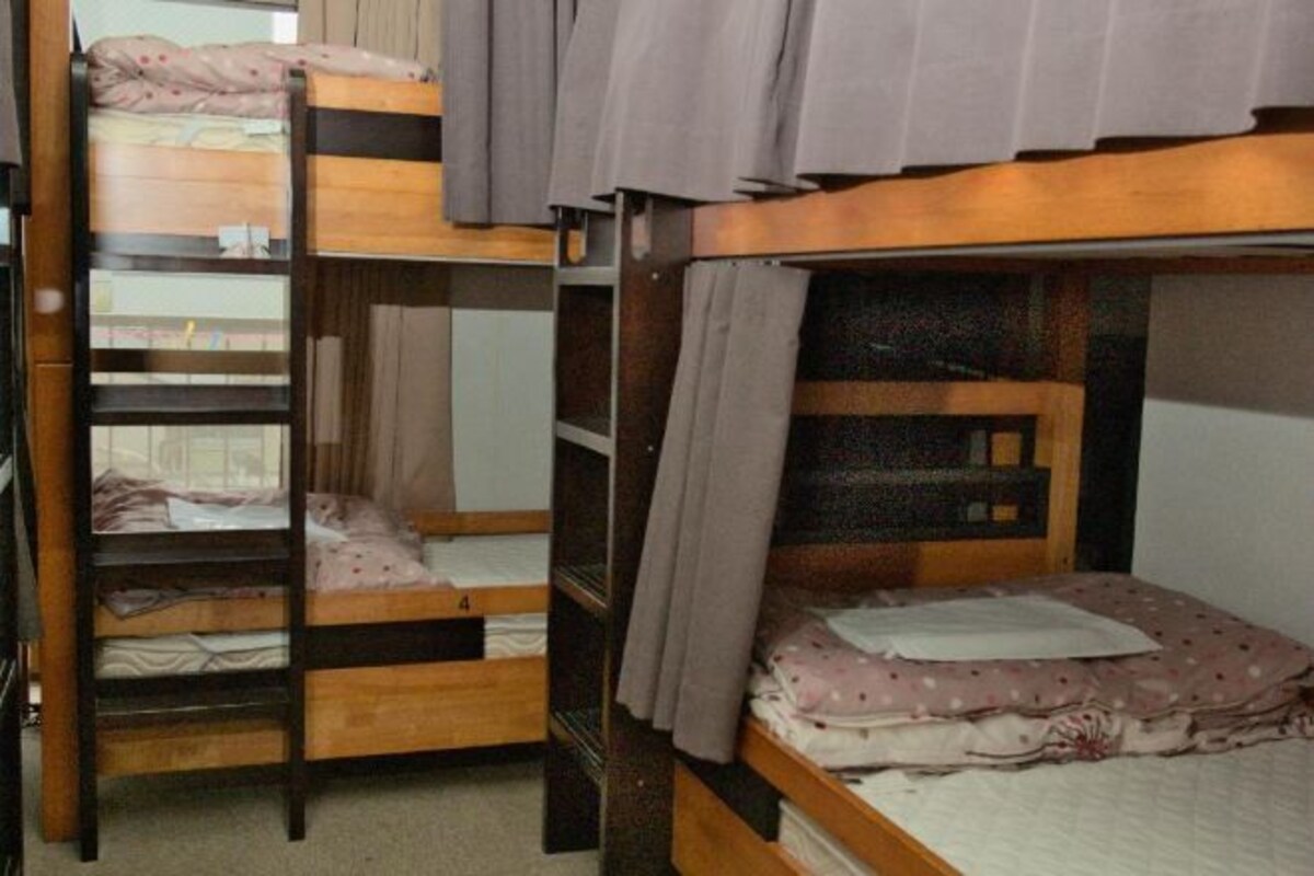 A bunk bed room with wooden frames and curtains.