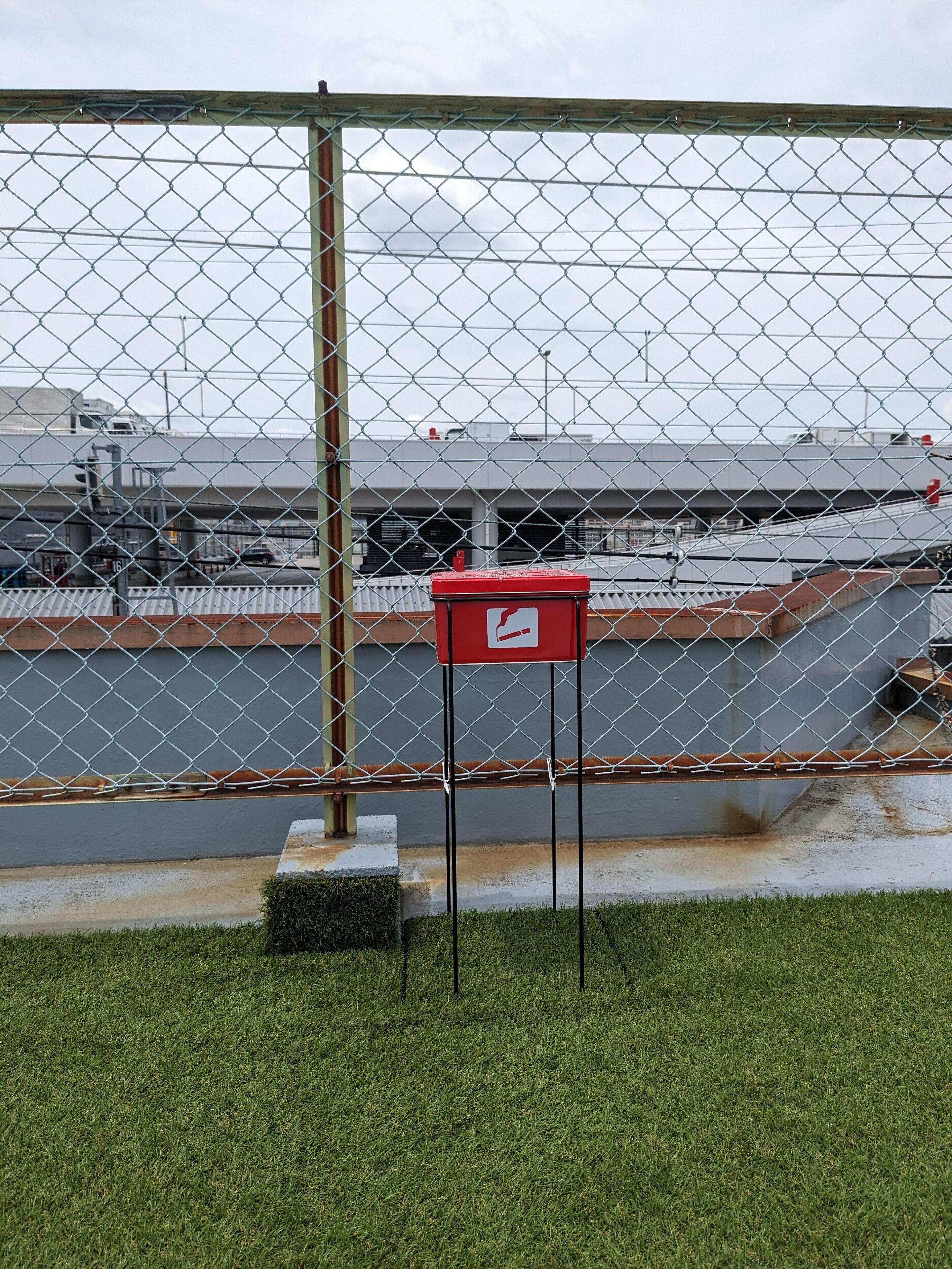 A chain-link fence with a red mailbox in the foreground.