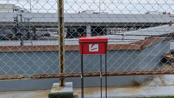 A chain-link fence with a red mailbox in the foreground.