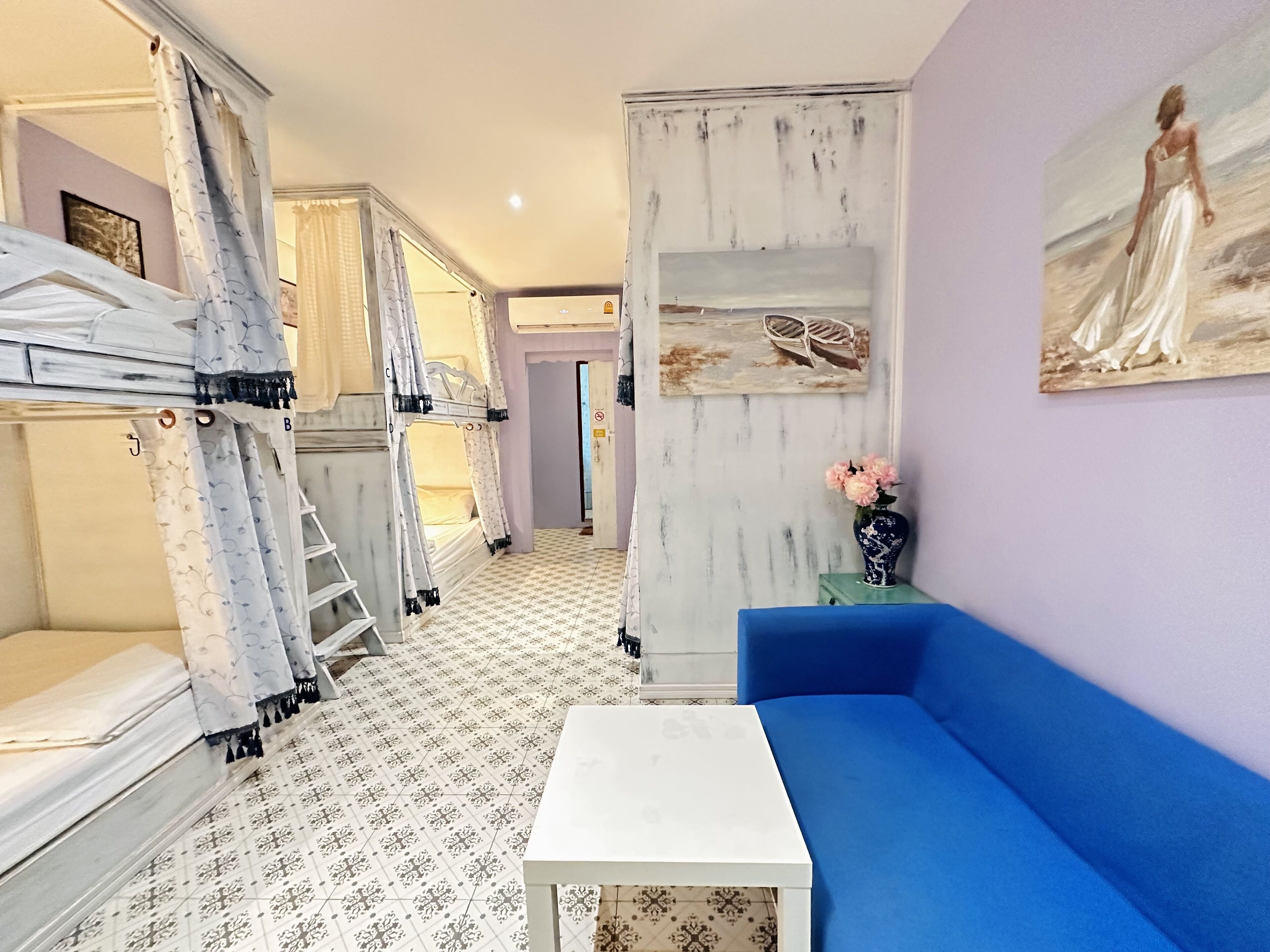 A room with bunk beds, a blue sofa, a small table, and a painting on the wall.