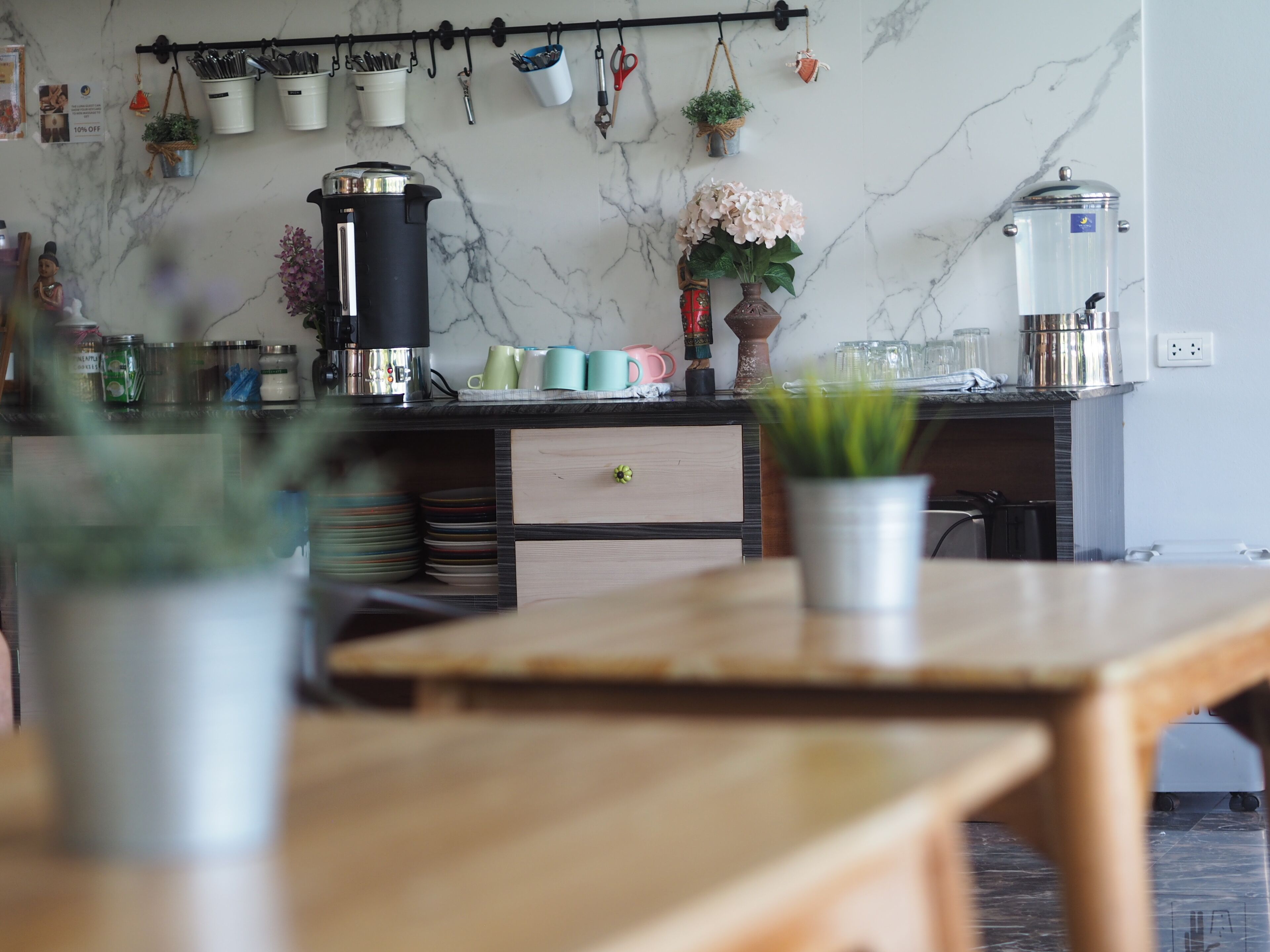 Ett kök med en väggbeklädnad av marmor, en kaffemaskin och olika köksredskap som hänger på en hylla.