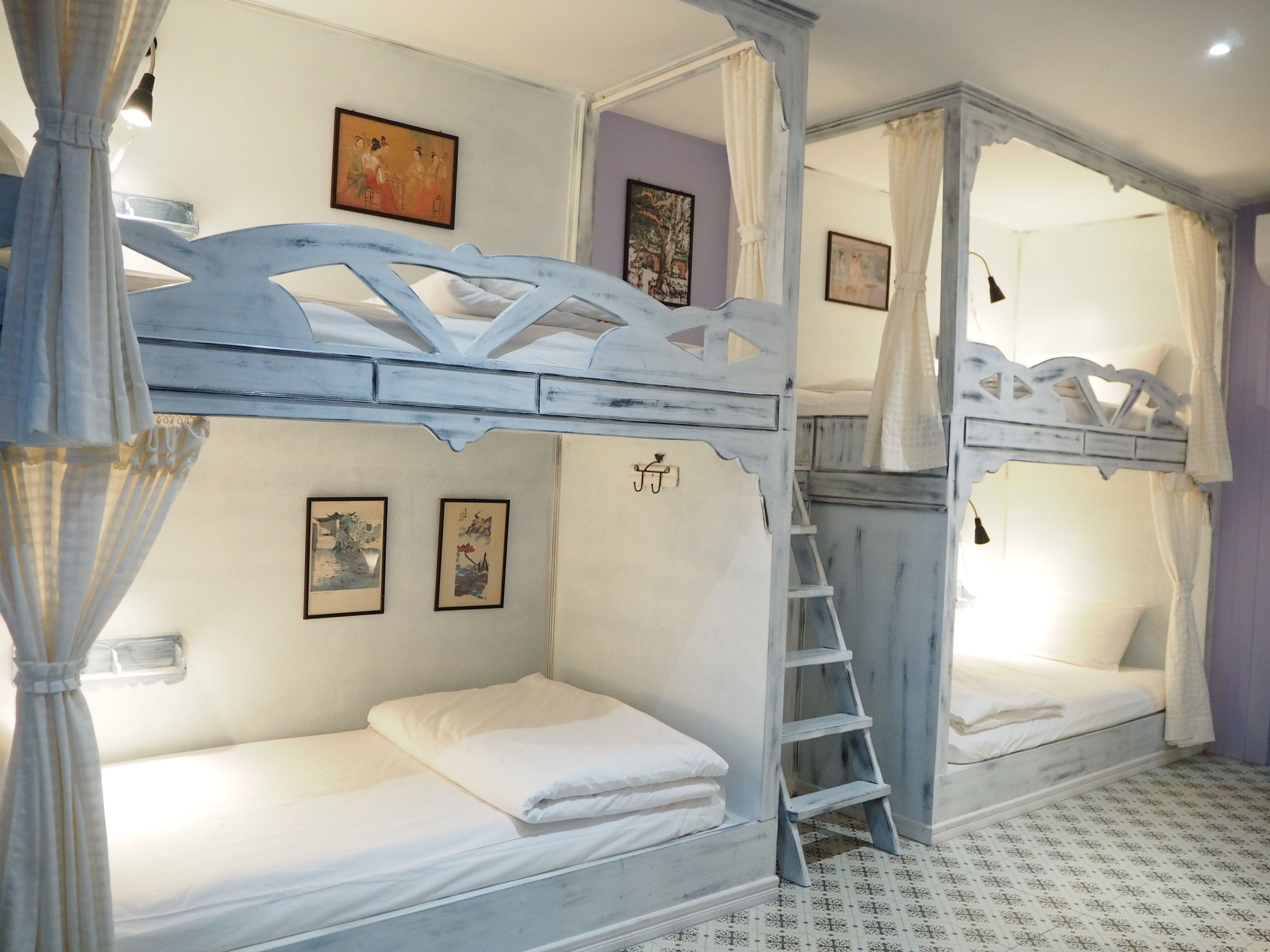 Une chambre avec deux lits superposés, une échelle et des œuvres d’art accrochées aux murs.