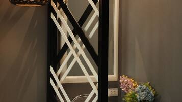 Un baño moderno con un separador geométrico blanco y negro, un lavamanos blanco y un jarrón decorativo con flores.