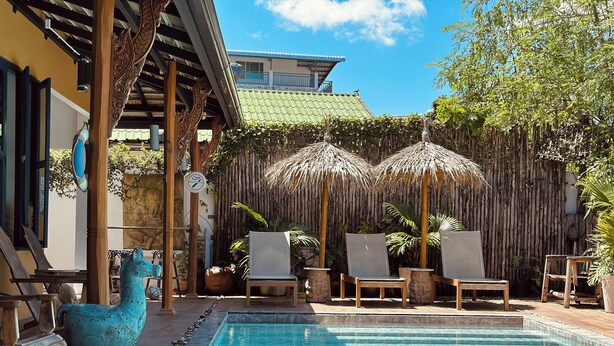 A pool area with lounge chairs and a decorative sculpture. - The Luna Hostel (Sa Khu)