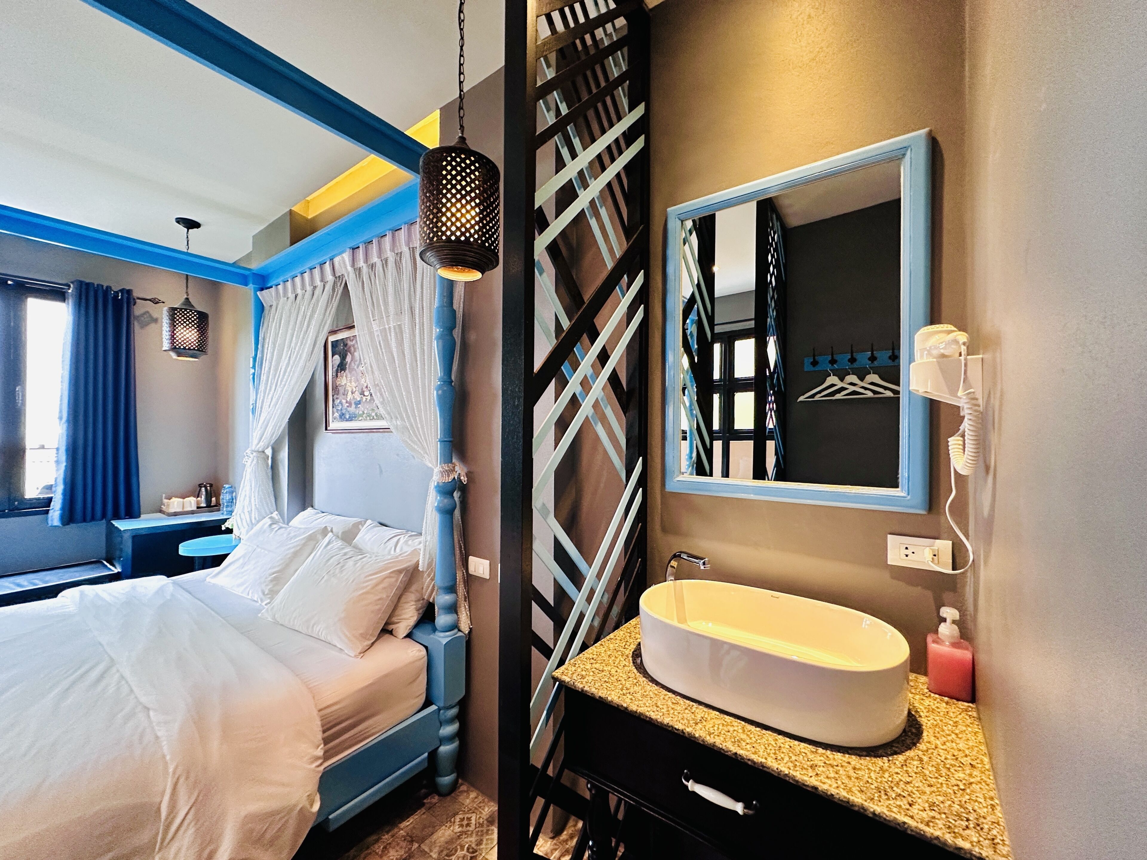 A hotel room with a bed, a bathroom with a sink, and a mirror.