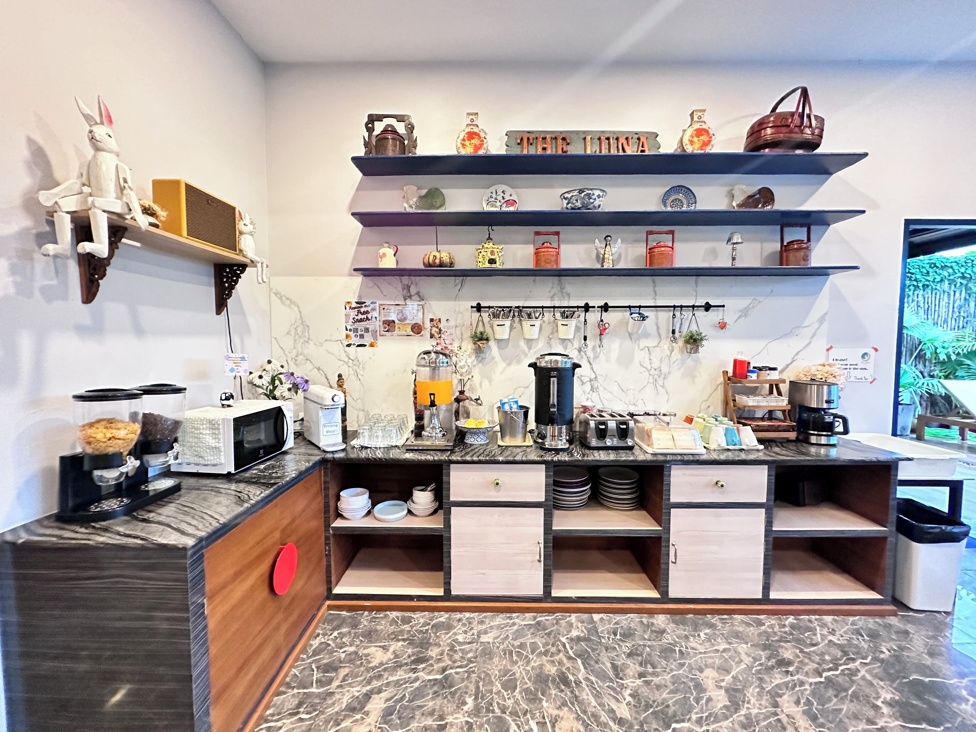 A kitchen with a marble countertop, a coffee machine, a toaster, and a shelf with decorative items.