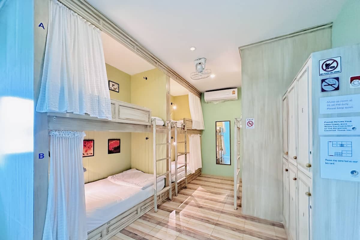 Habitación tipo dormitorio con literas, un espejo, un armario y un cartel con las normas de la habitación.