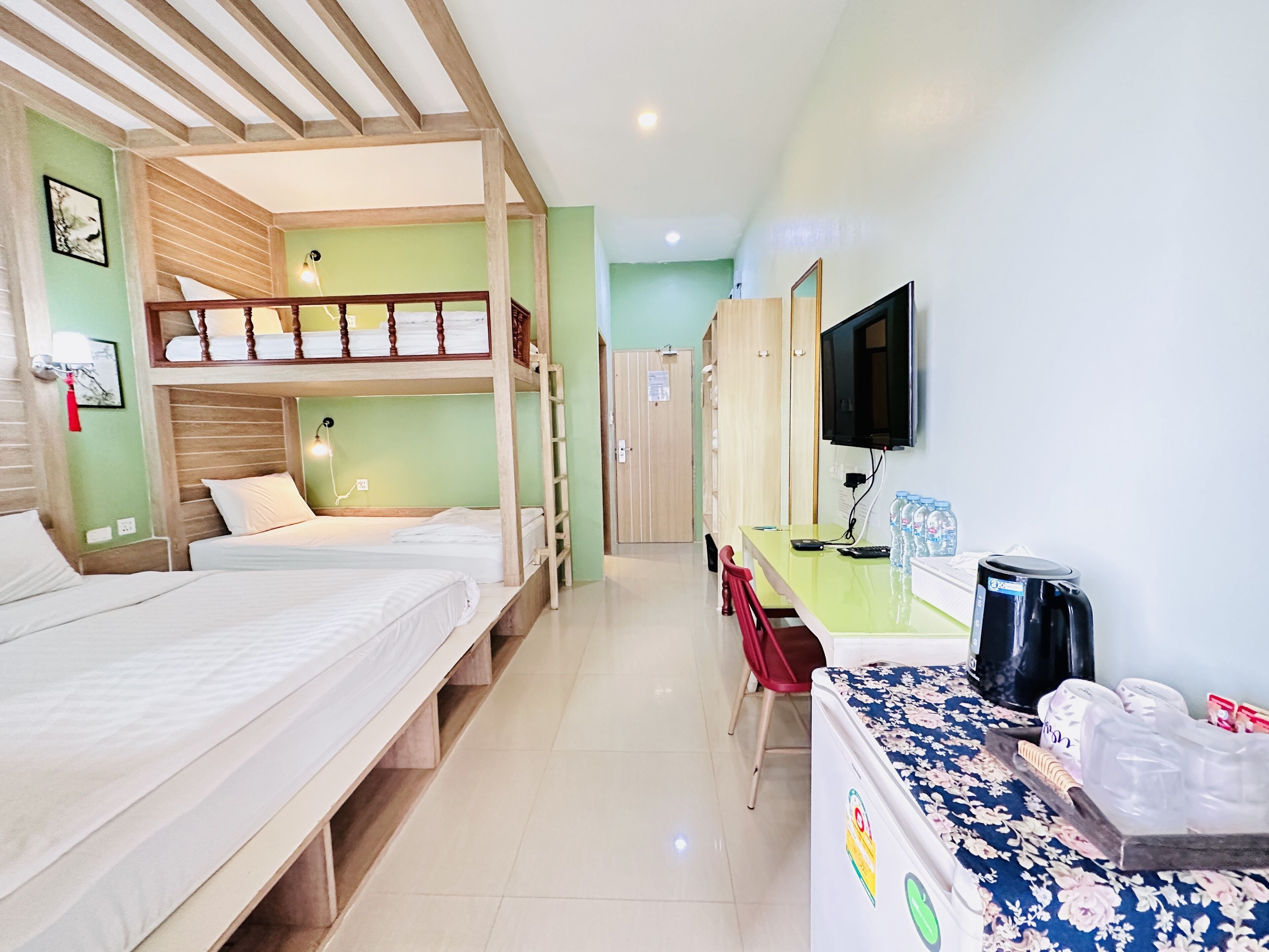 Une chambre d’hôtel avec des lits superposés, un bureau avec une télévision et un coin café.