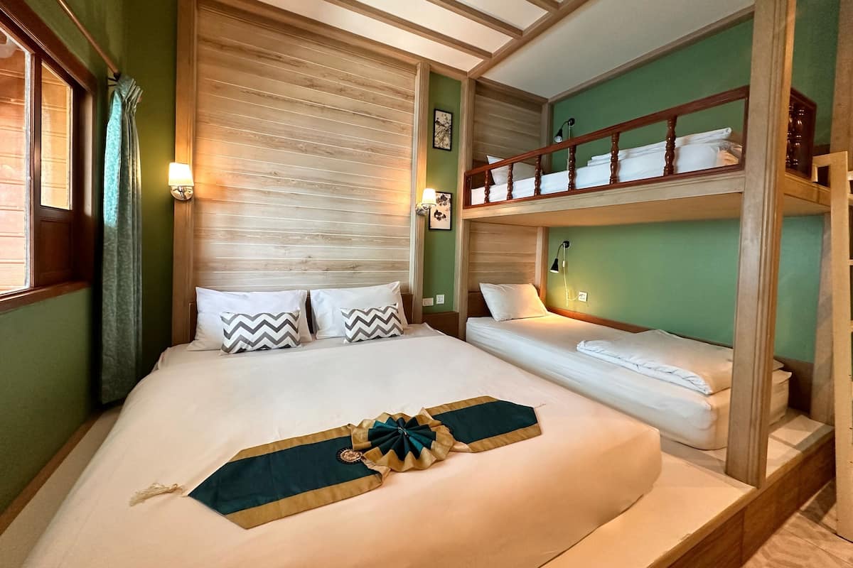 Una habitación de hotel con una cama grande, una cama nido y una ventana con cortinas.