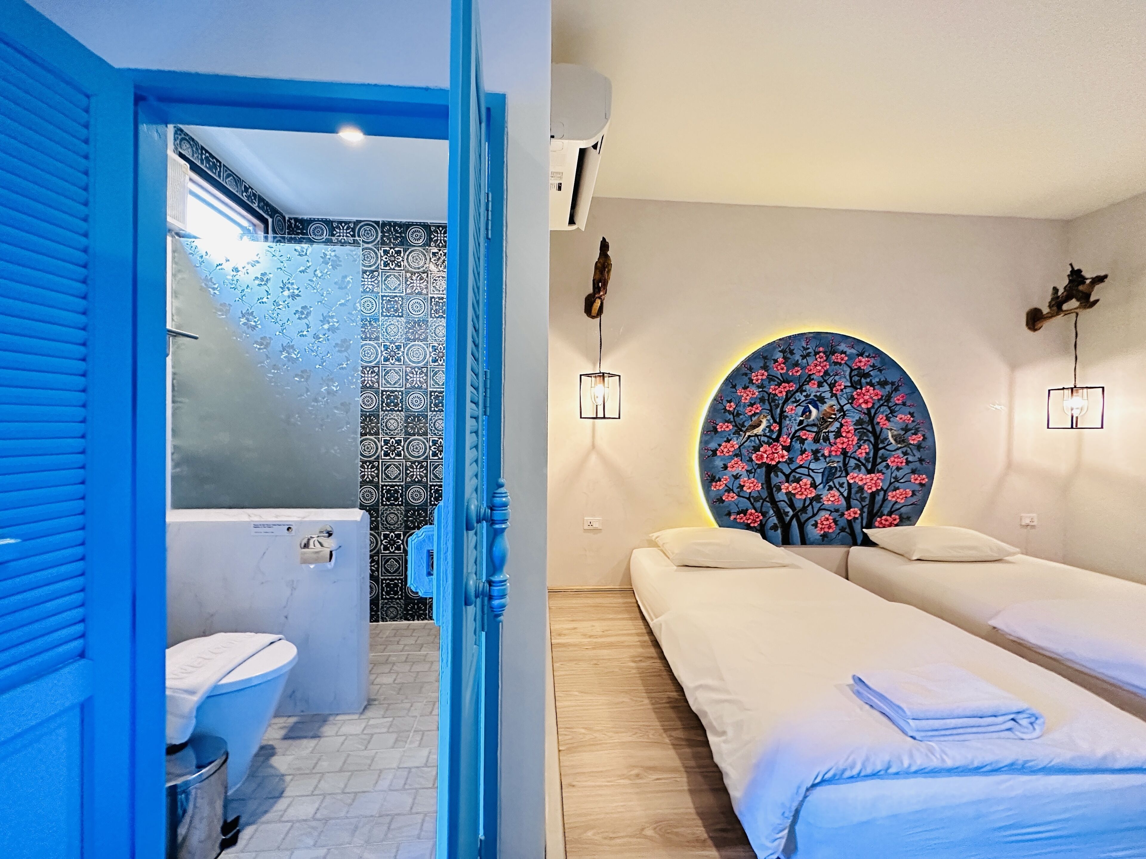Una habitación de hotel con baño, una cama y un cuadro floral circular en la pared.