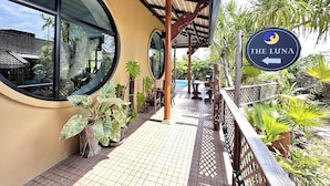 A covered outdoor area with a pool, potted plants, and a sign for 'The Luna'. - The Luna Hostel (Sa Khu)