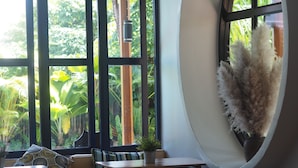 A room with a curved window, a sofa, a table, and a chair. - The Luna Hostel (Sa Khu)