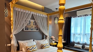 A four-poster bed with sheer curtains, a decorative wall hanging, and a bedside table with a flower vase. - The Luna Hostel (Sa Khu)
