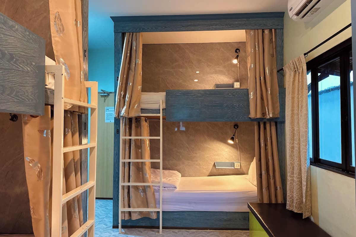 Una habitación pequeña con literas, un escritorio y una escalera.