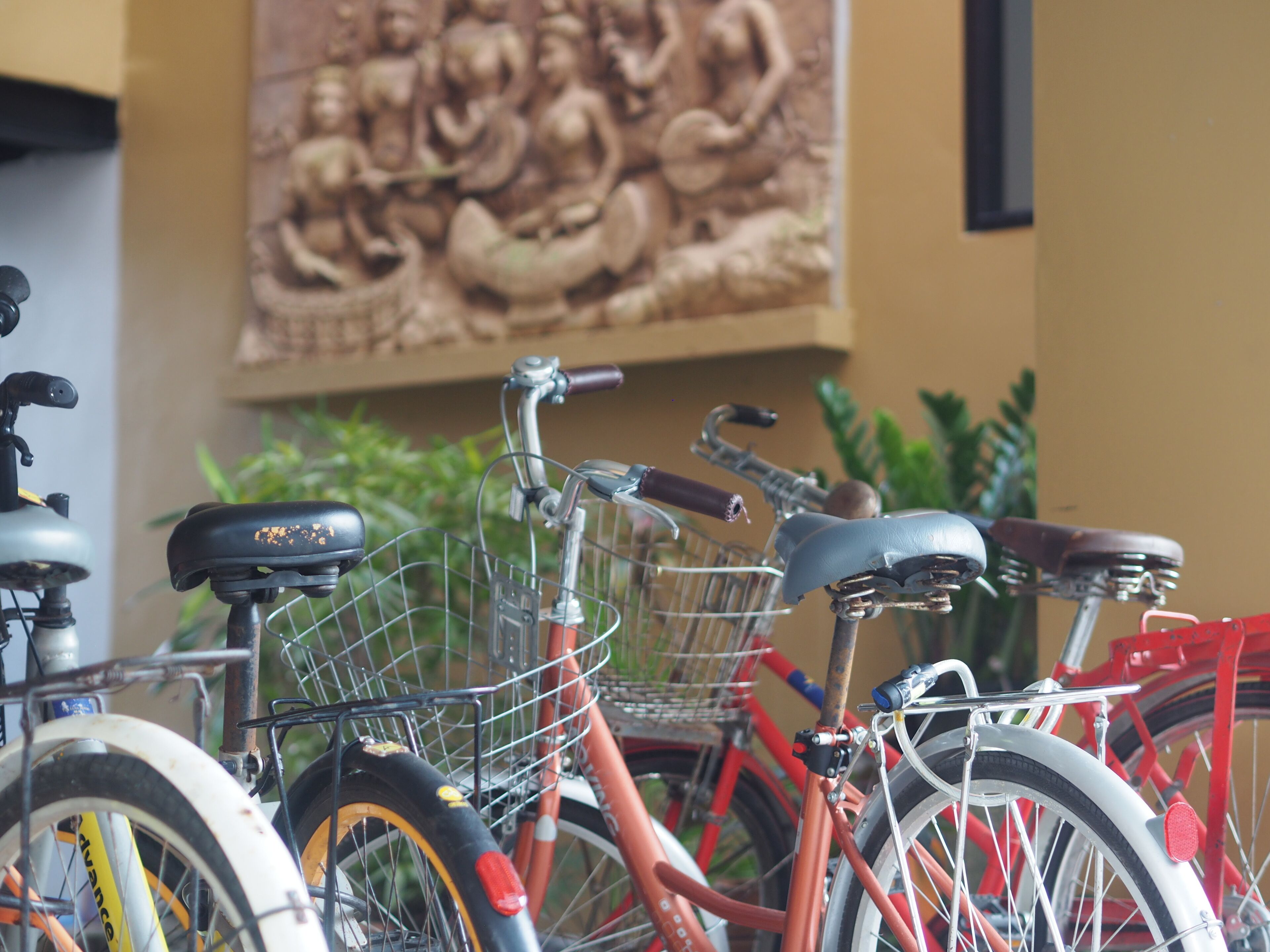 A row of bicycles parked indoors, with a mural in the background.