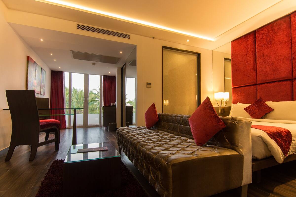 A modern hotel room with a large bed, a desk, and a view of palm trees.