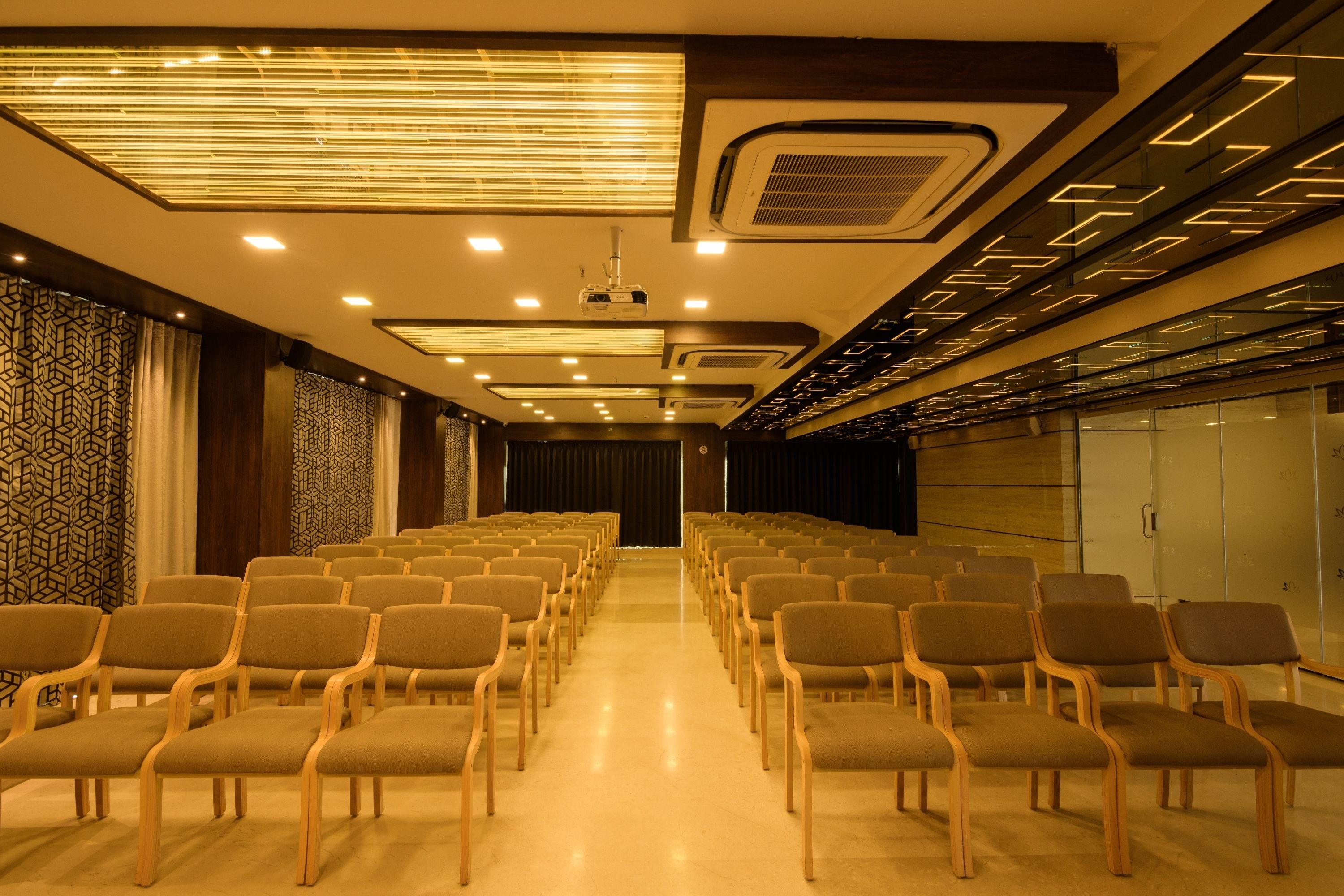 A conference room with rows of chairs, a projector, and a patterned wall.