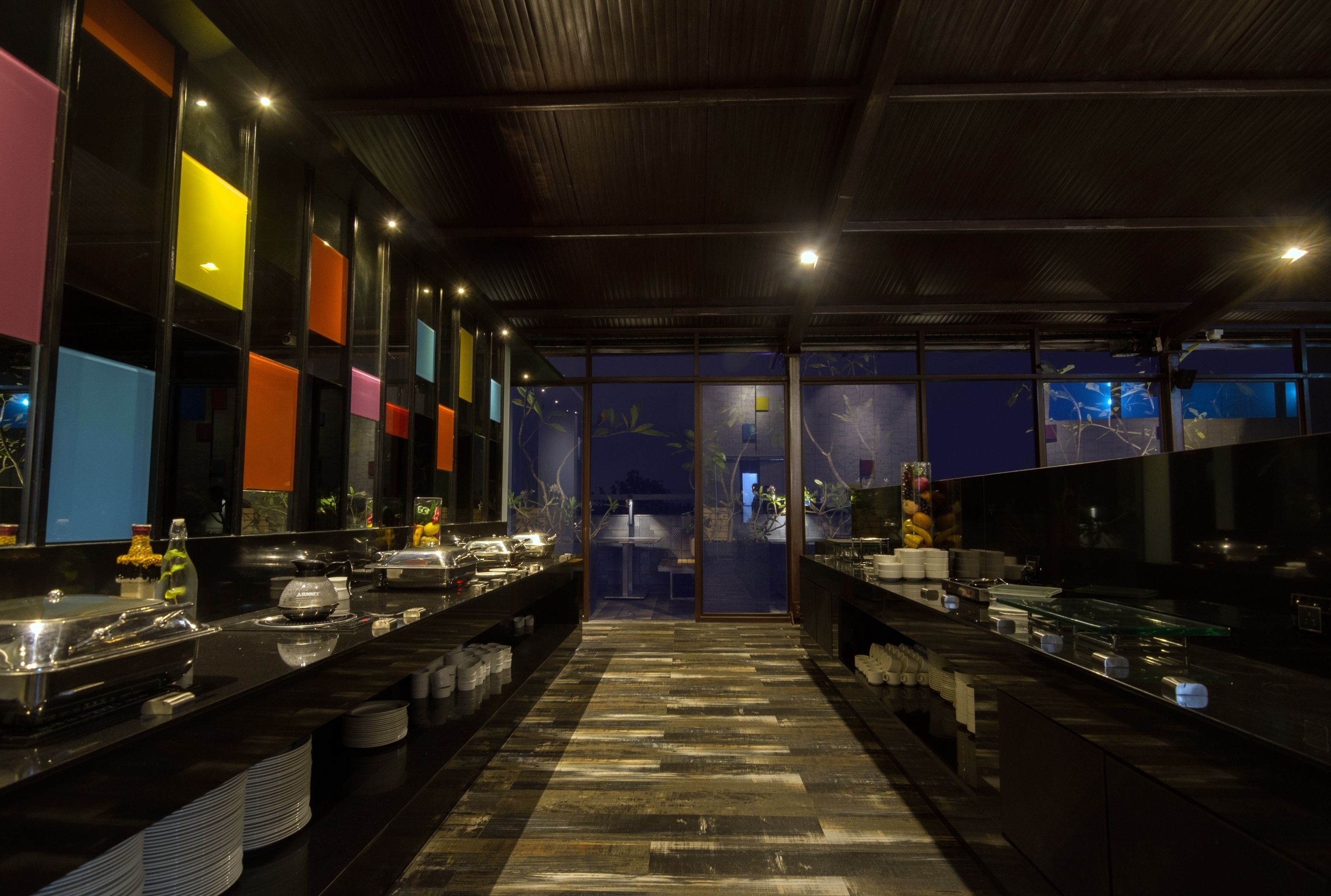Una cocina moderna con una encimera larga, vitrinas de vidrio y una variedad de alimentos.