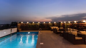 A rooftop pool area with a clear view of the city skyline at dusk. - Roopa Elite (Mysore)