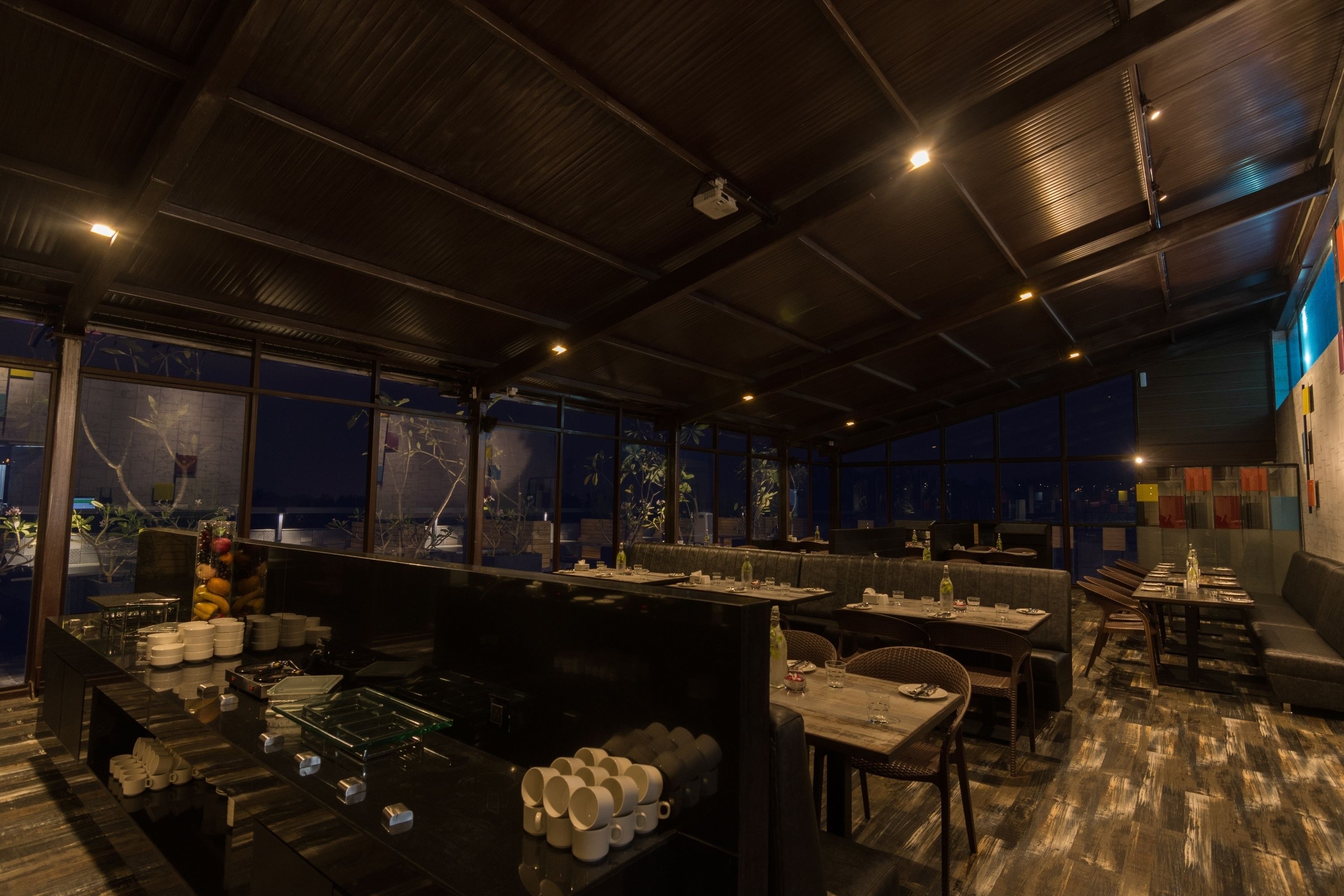 A modern restaurant with high ceilings, large windows, and a variety of seating arrangements.