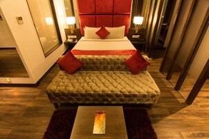 A hotel room with a large bed, a sofa bed, a bedside table, and a mirror.