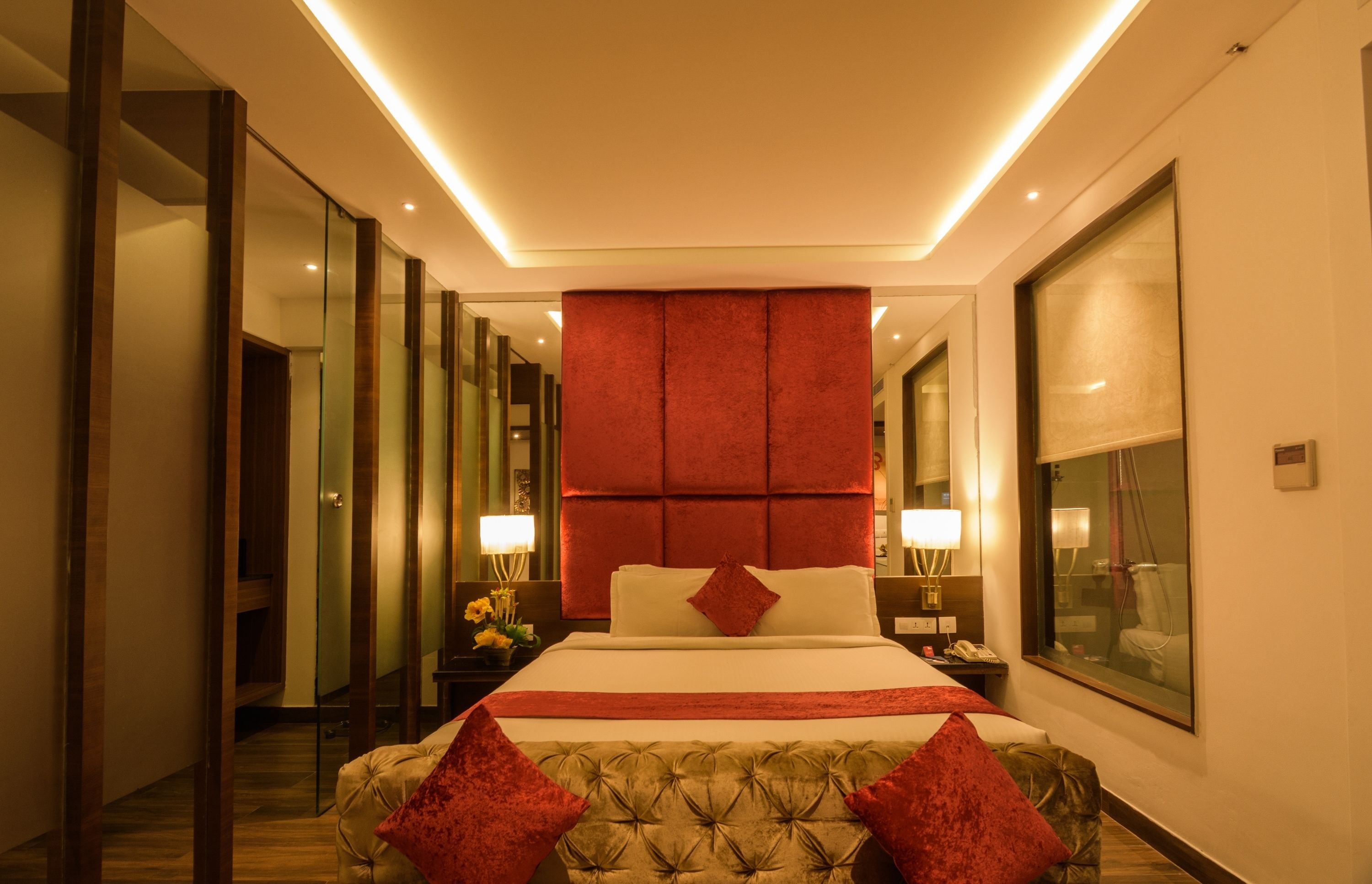 Una habitación de hotel moderna con una cama grande, una pared de acento roja y un ventanal amplio.