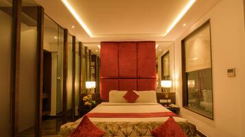 A modern hotel room with a large bed, a red accent wall, and a large window.