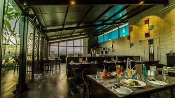 A modern restaurant with high ceilings, large windows, and a view of the cityscape.