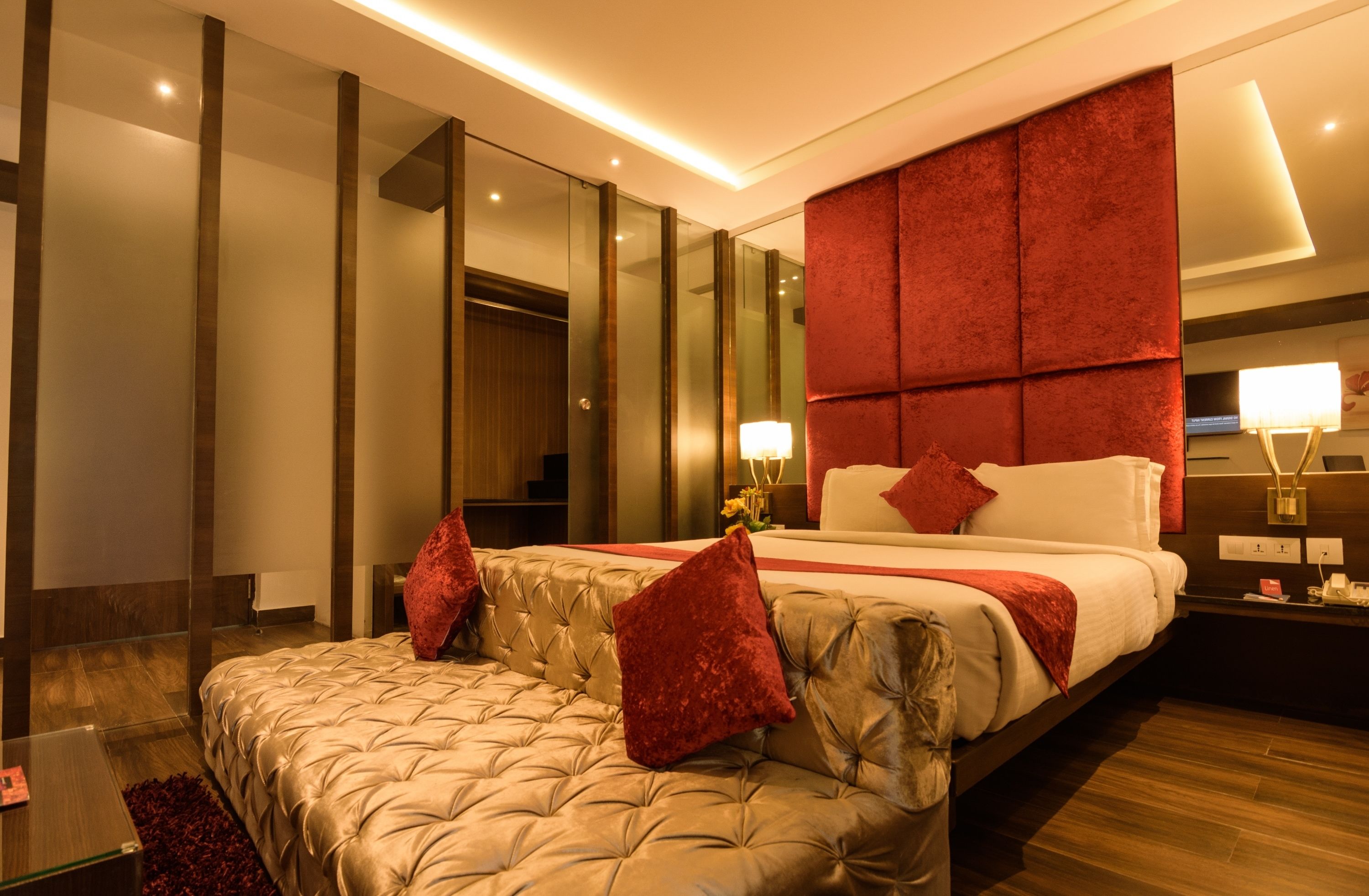 Une chambre d’hôtel moderne dotée d’un grand lit, d’un coin salon, d’un miroir et d’une table de chevet avec une lampe.