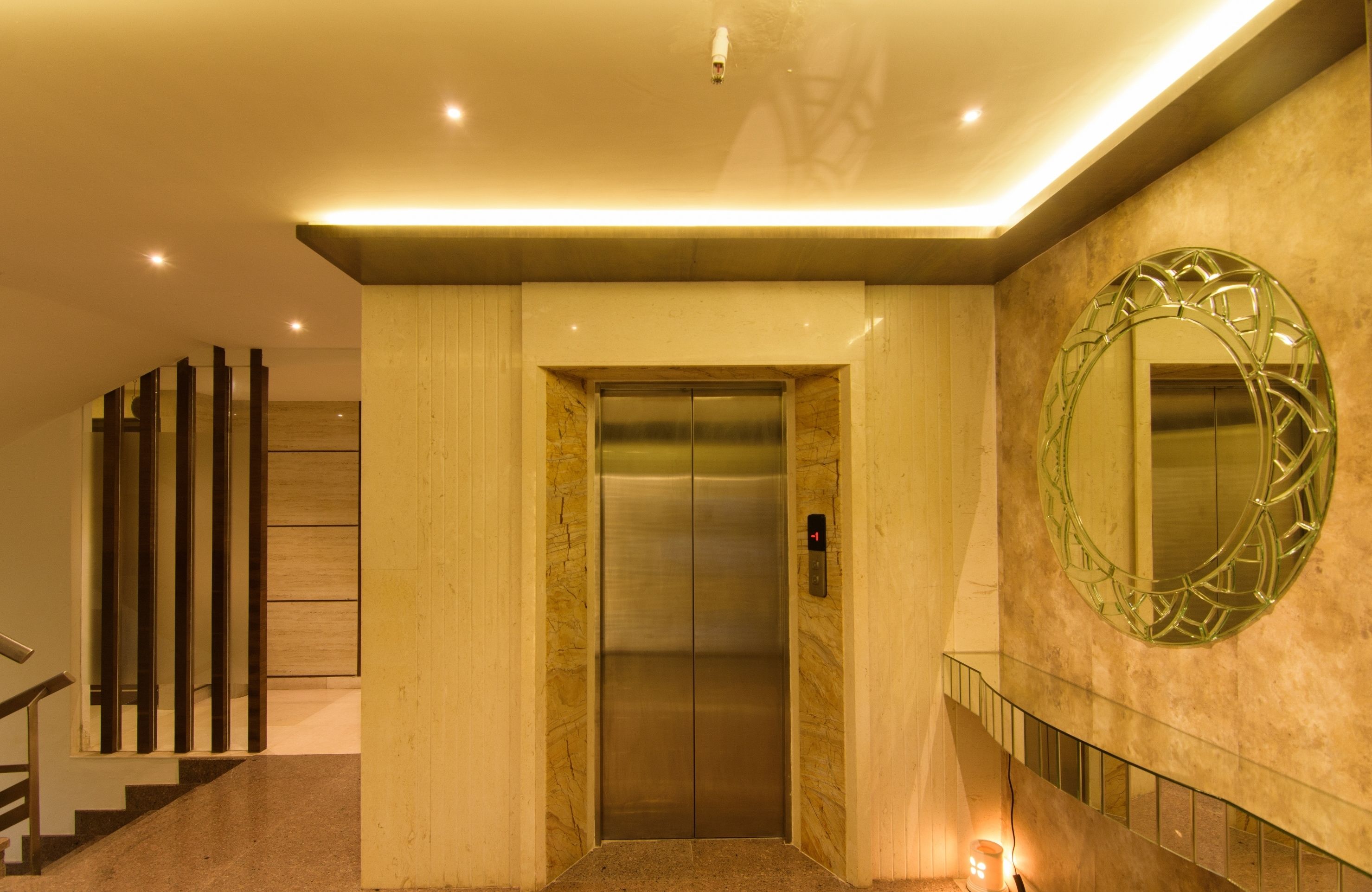 An elevator in a modern building with a marble wall and a large mirror.